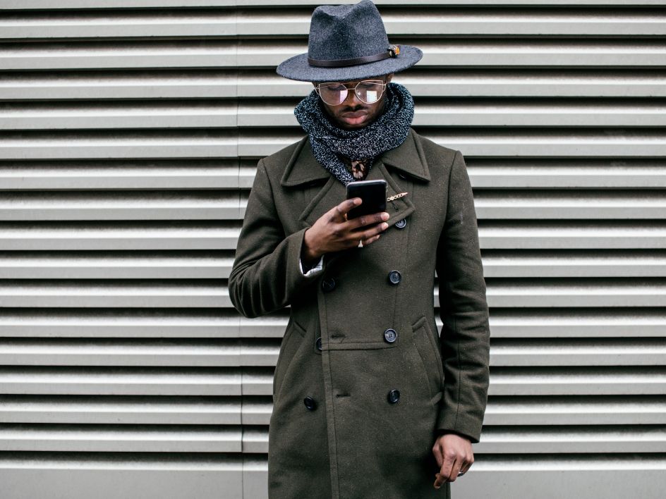 Man in trench coat looking at phone